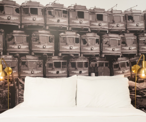 A wallpaper of red line buses frame a bed at The Redline Venice Hotel.