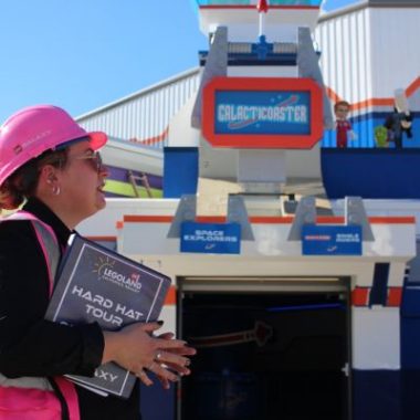 A LEGOLAND California team member wearing a pink hard hat stands outside the Galacticoaster entrance during a LEGO Galaxy media preview.