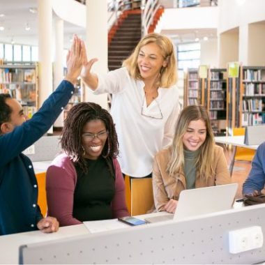 Diverse group of teachers celebrating student success in a school library