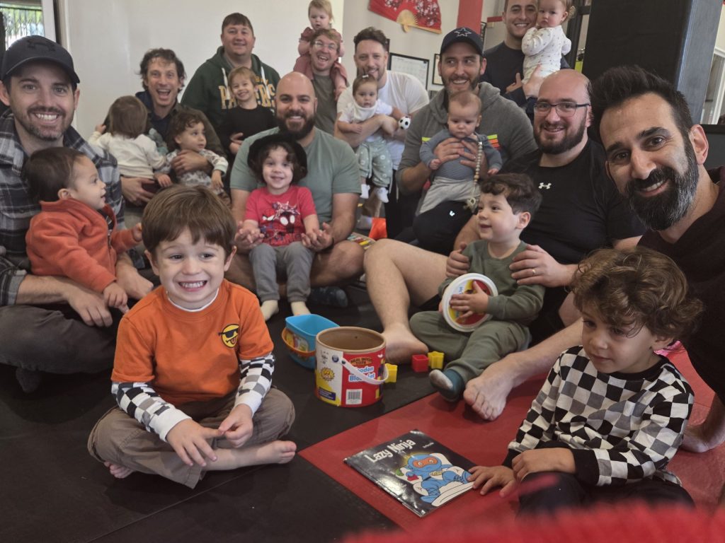 A group of dads and their kids posing for a photo.