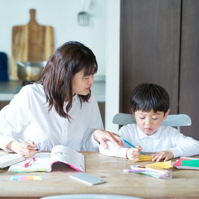 Child working on homework at kitchen table with parent support.