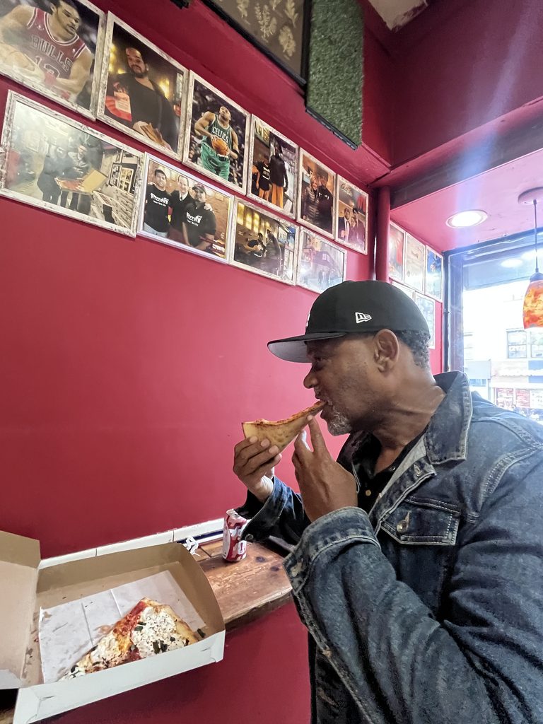 Man eating pizza at counter in Harlem.